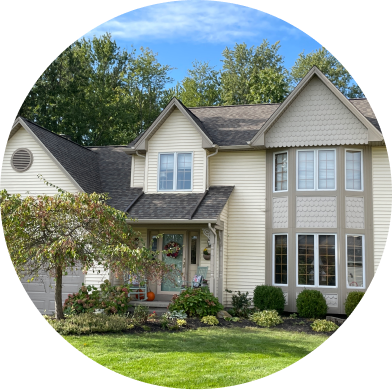 Beautiful two-story beige house with large windows and manicured lawn