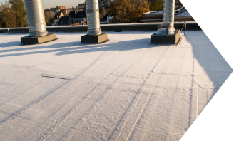 Commercial flat roof with white membrane showing tire tracks and construction equipment