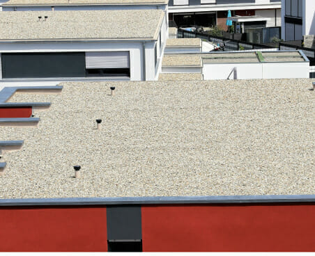 Flat commercial roof with gravel surface and HVAC equipment on modern building