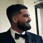 Professional man in black tuxedo with bow tie smiling in formal indoor setting